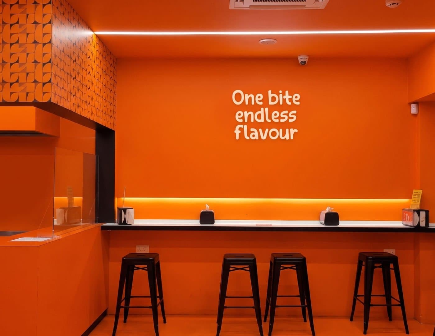OnBite restaurant interior featuring a bold orange color scheme, branded wall design, counter seating, and modern lighting