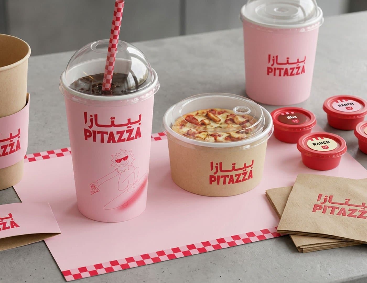 PITAZZA restaurant packaging featuring branded cups, food containers, napkins, and signature red and pink branding