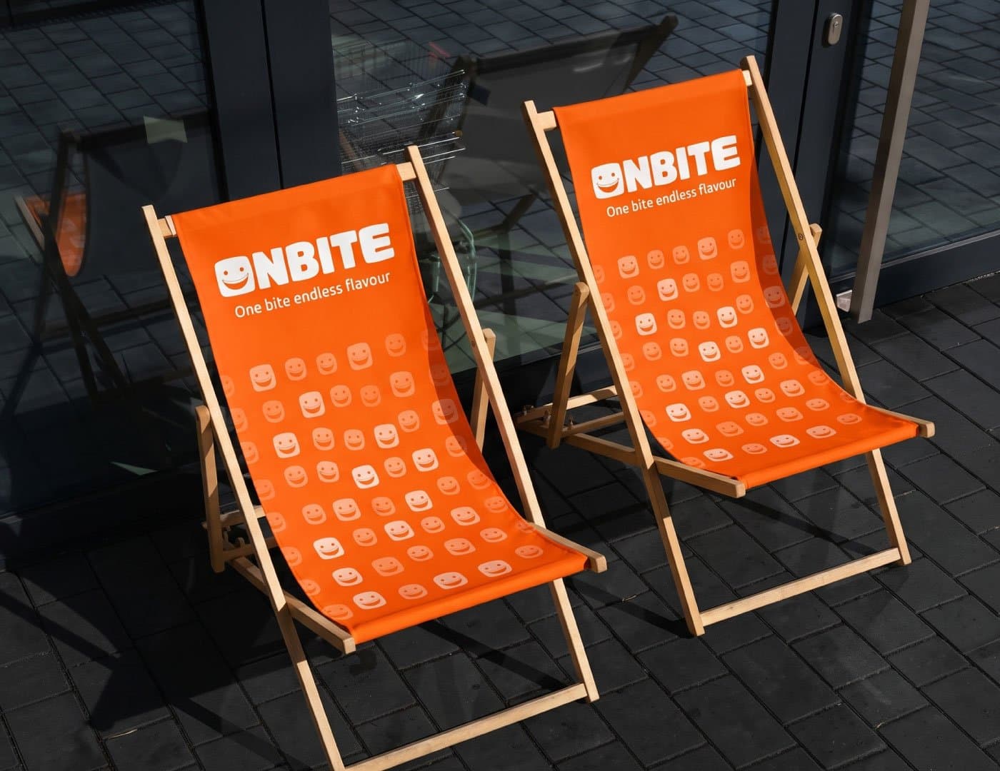 OnBite branded outdoor deck chairs featuring orange upholstery, repeating smile icon pattern, and restaurant branding